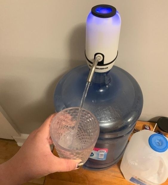 Reviewer using the dispenser to pour water from the jug, hands-free