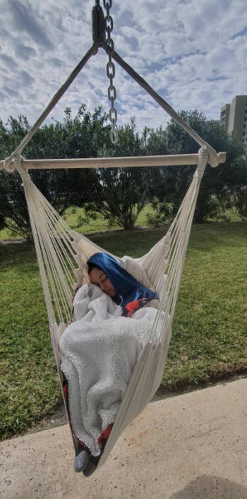A reviewer lounges in a white hanging hammock chair