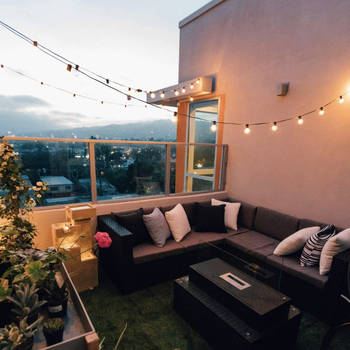 A patio at dusk with round string lights on a black wire 