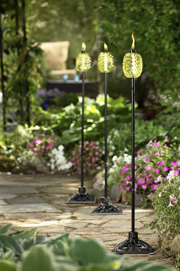 Pineapple-shaped tiki torches in a line on a garden pathway
