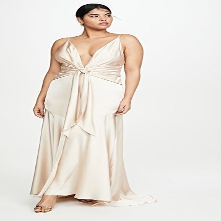 a model in a satin champagne colored gown with a low v-neck cut and thin straps