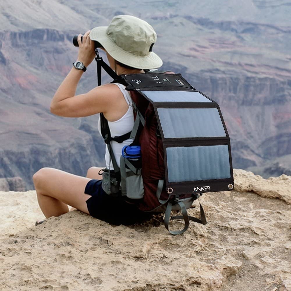 Hiker with solar panel attached to backpack to absorb sunlight