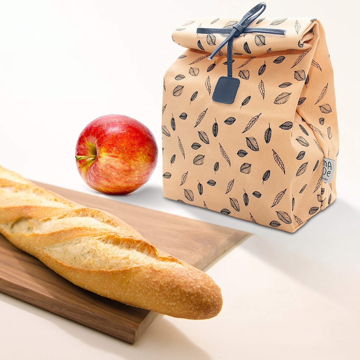 The printed lunch bag on a surface with bread and an apple