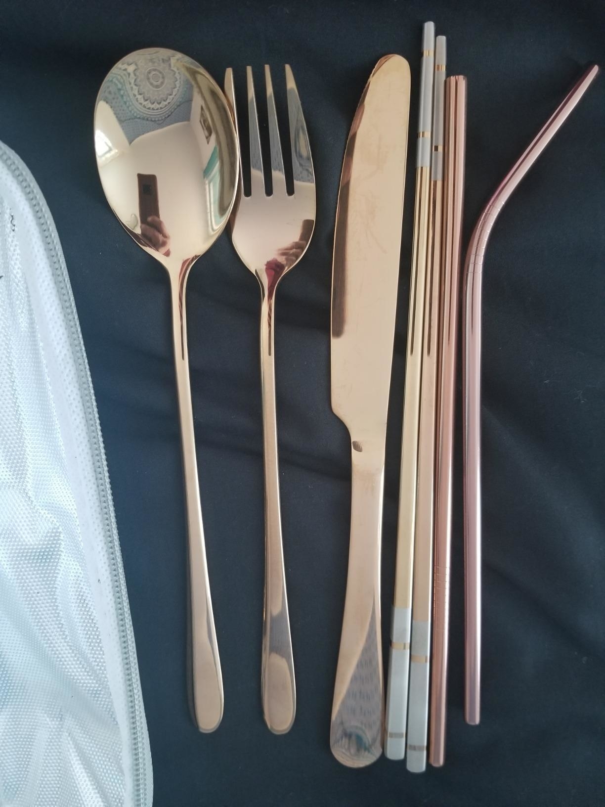 A set including a rose gold spoon, fork, knife, and straws