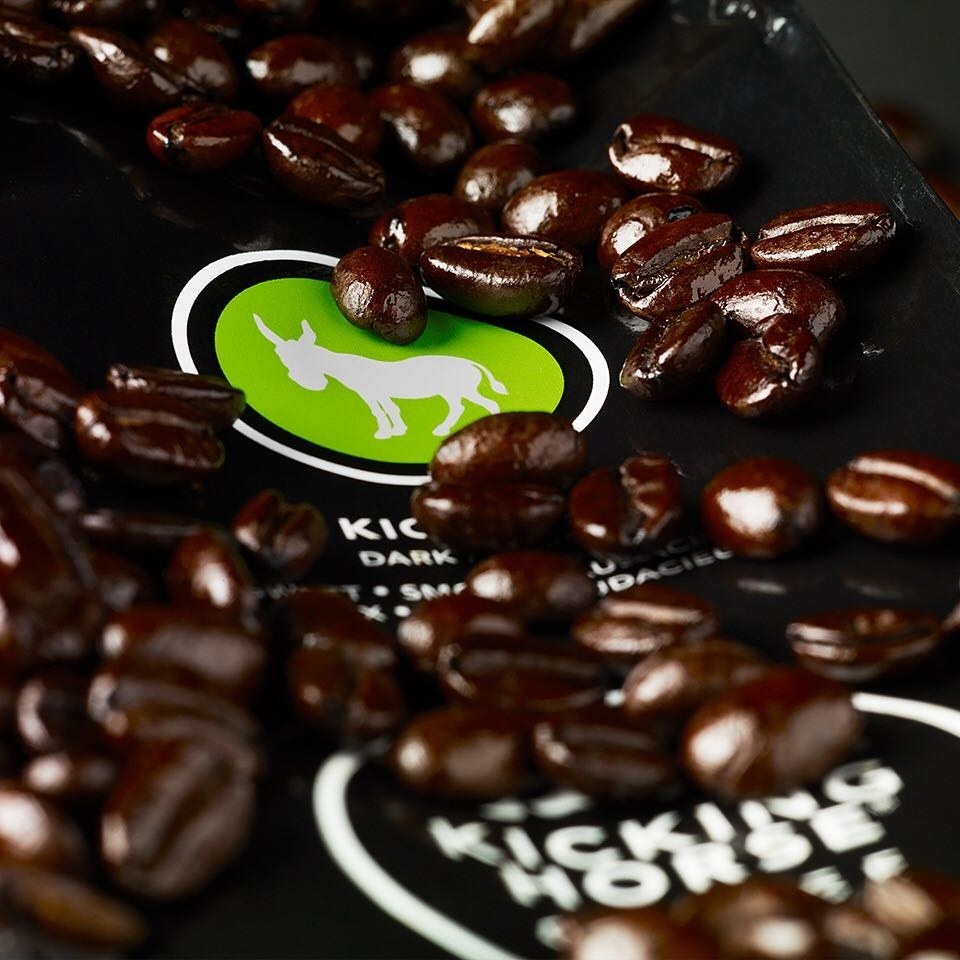 A pile of coffee beans placed on an open package of coffee