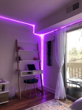 Reviewer using the light string in purple to line a corner of the room 