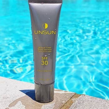 bottle of sunscreen next to a pool