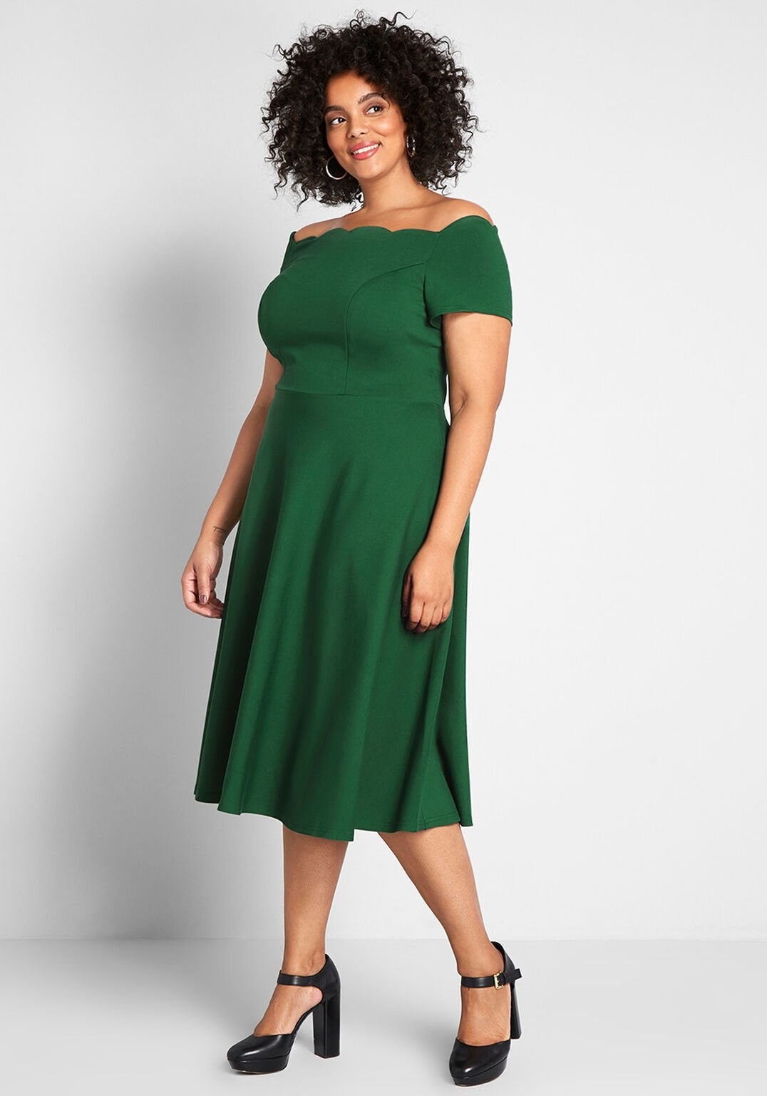 a model in the mid-length dress in emerald green