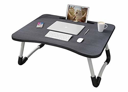 A grey foldable bed table with a smartphone, laptop, wireless keyboard and mouse, a cup of coffee, and a pen on it. There&#x27;s a tablet kept in the tablet slot.