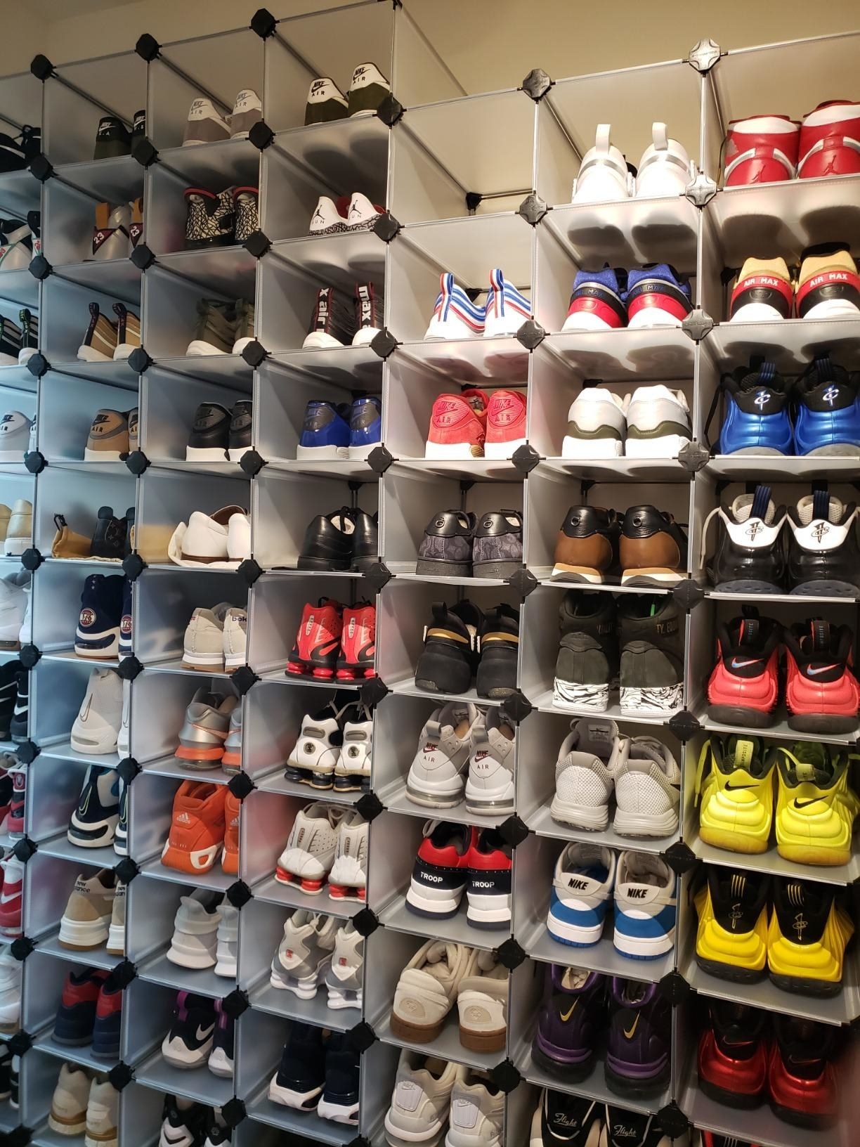 A closet with dozens of stacked cubes, all holding different pairs of shoes