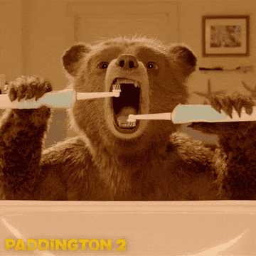 A GIF of Paddington Bear using two electric toothbrushes at the same time