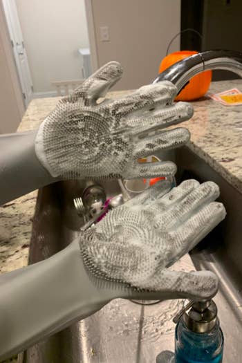 A reviewer wearing the gray gloves with the palms covered in suds