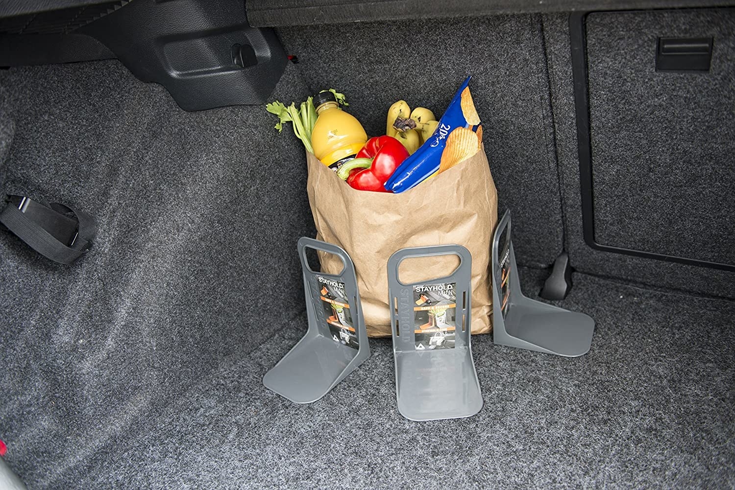 The L-shaped tools holding up a paper bag of groceries in a trunk