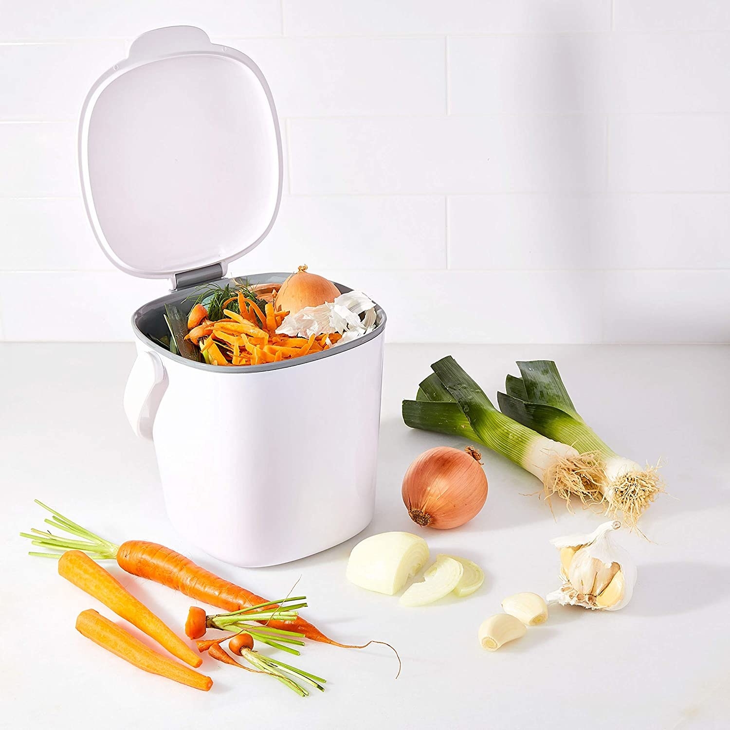 A white compost bin full of vegetable pieces 