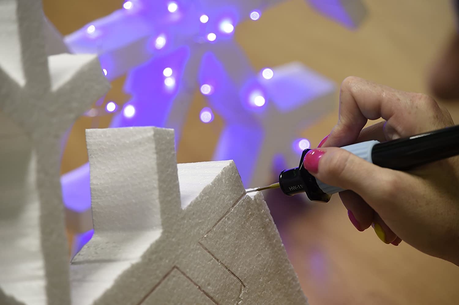 A person carving giant snowflakes out of foam with the heat tool