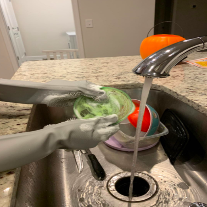 The same reviewer washing dishes with the soapy gloves