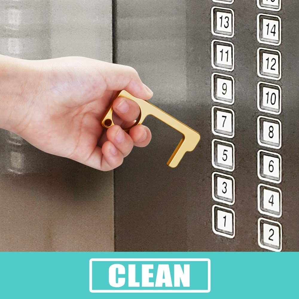 A hand using the tool to push an elevator button