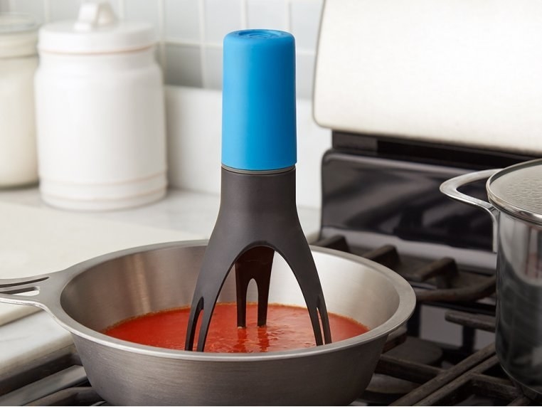 The pot stirrer with three-prong legs in a pot of red sauce