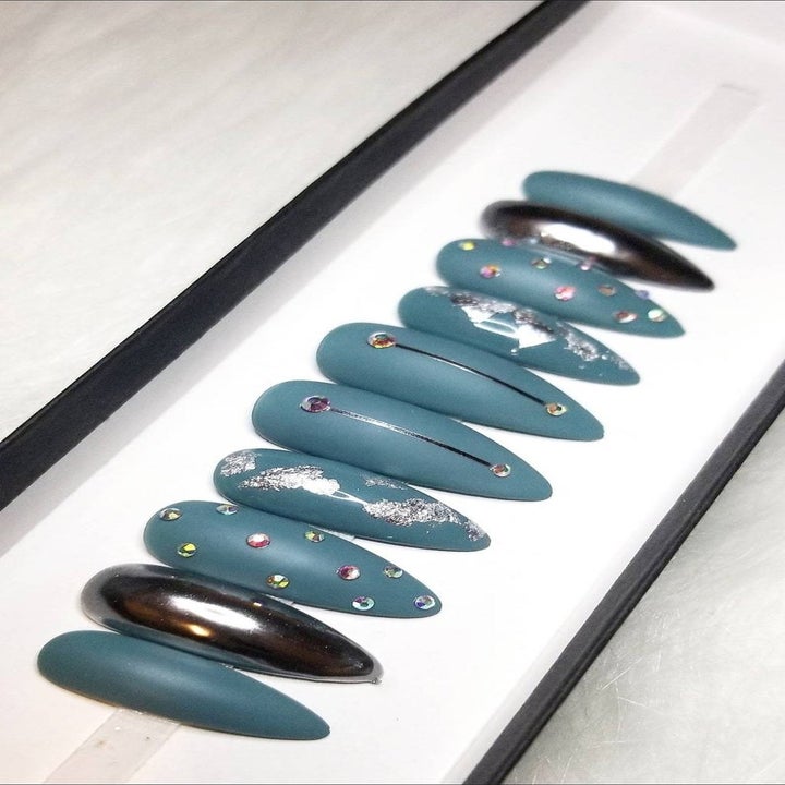 pointy shape press on nails in a box in matte blue with embellishments and metallic silver accent nails