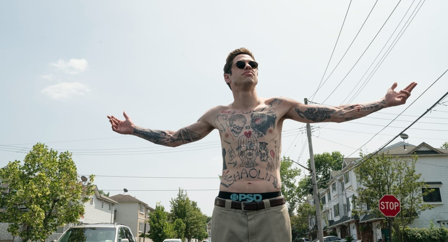 A shirtless Pete Davidson shows off his tattoos in a still from The King of Staten Island
