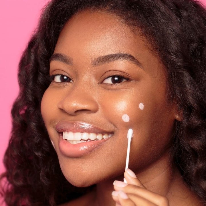 A person applying blemish drying lotion to their face with the applicator