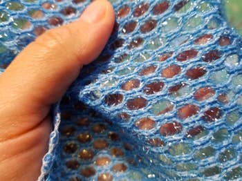 A reviewer's hand showing a close-up of the open-weave cloth
