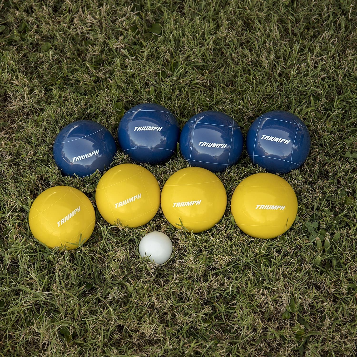 four yellow and four blue bocce balls with one small white ball in grass