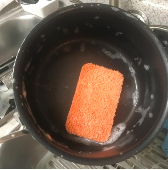 A reviewer photo of the orange, sudsy sponge in a pot