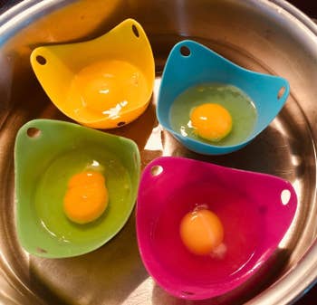 The cups holding a raw egg while sitting in a pot of water