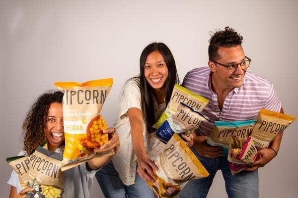Pipcorn founders hold up all the bags of cheese balls 