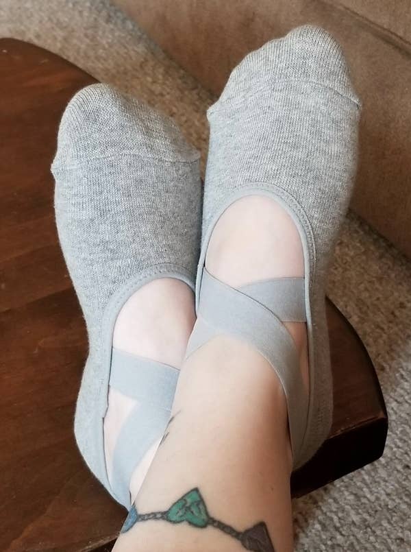 A reviewer image of feet wearing the gray socks with two crossover elastic straps on the top of the foot 