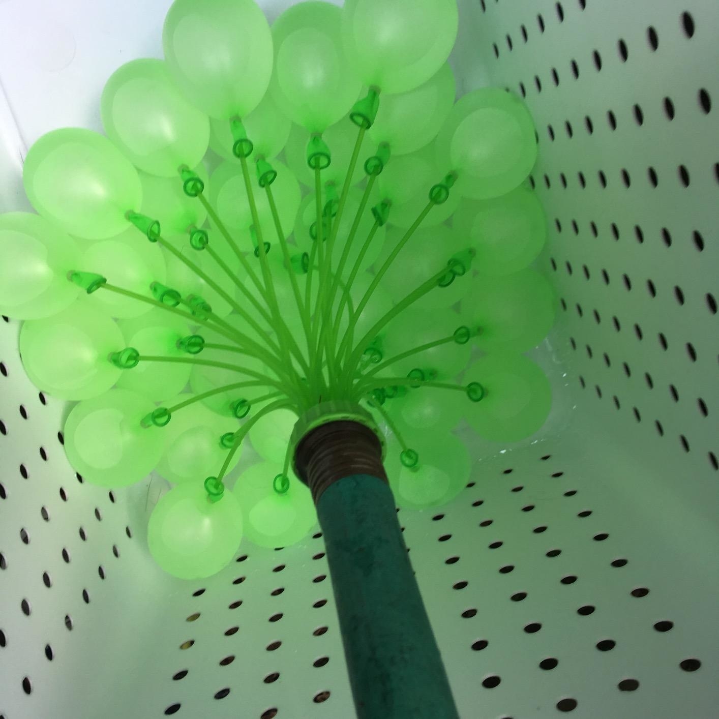 hose connected to a contraption that inflates a bunch of water balloons at once