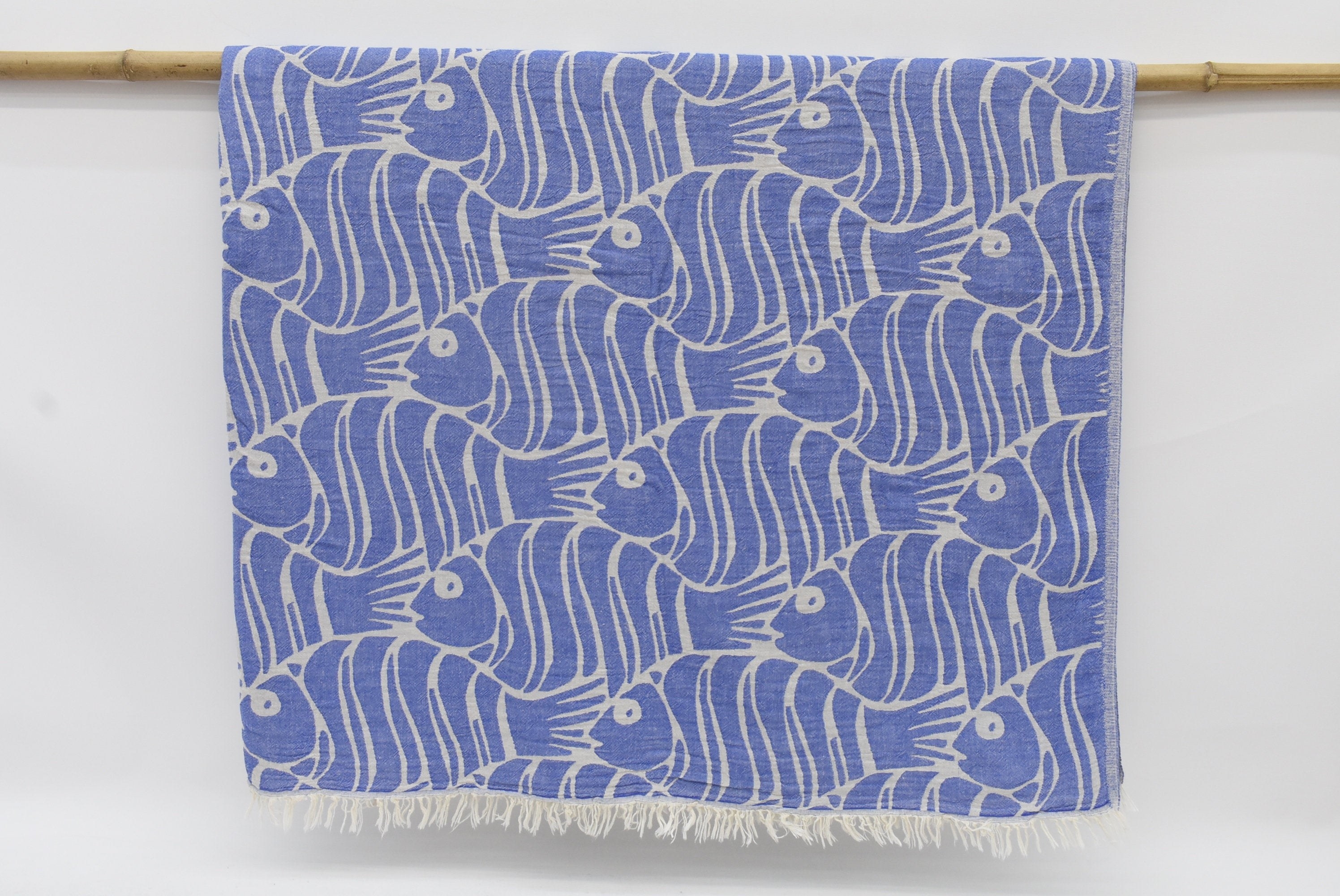 A blue fish-patterned throw blanket against grey background 