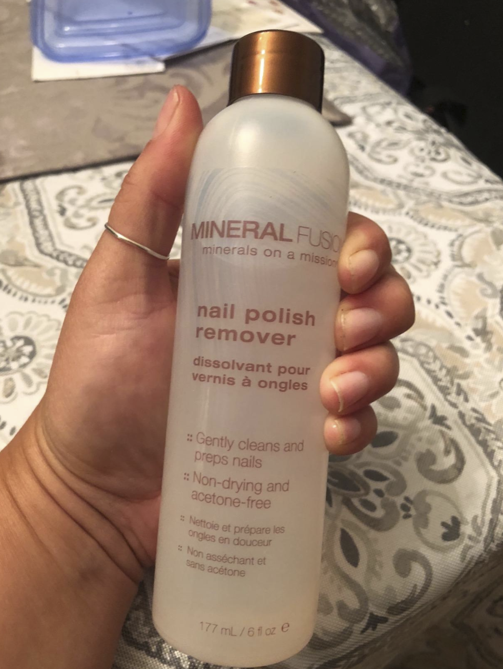 A reviewer&#x27;s hand holding a bottle of the remover. It has the brand name &quot;Mineral Fusion&quot; on it. 