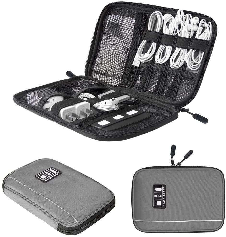 A small rectangular fabric case is open with lots of small elastic bands and mesh pockets inside holding charging cords, headphones, and plug adapters