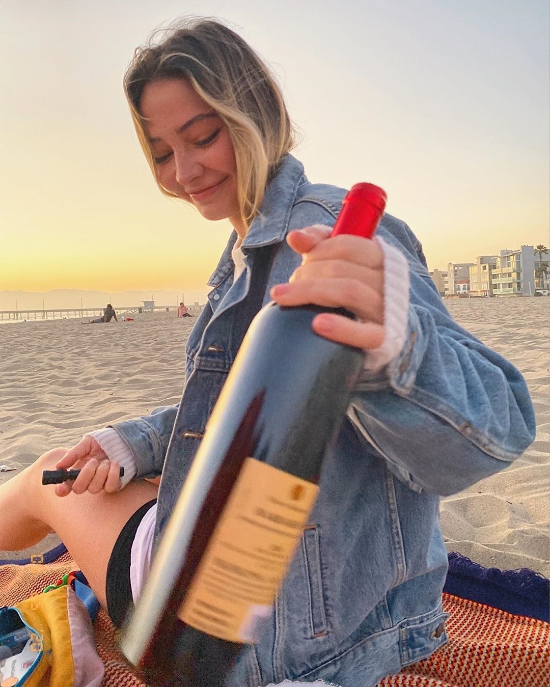  Madelyn Cline holds a bottle of wine at the beach. 