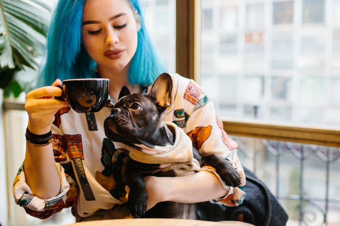 Woman drinking coffee and holding her French bulldog