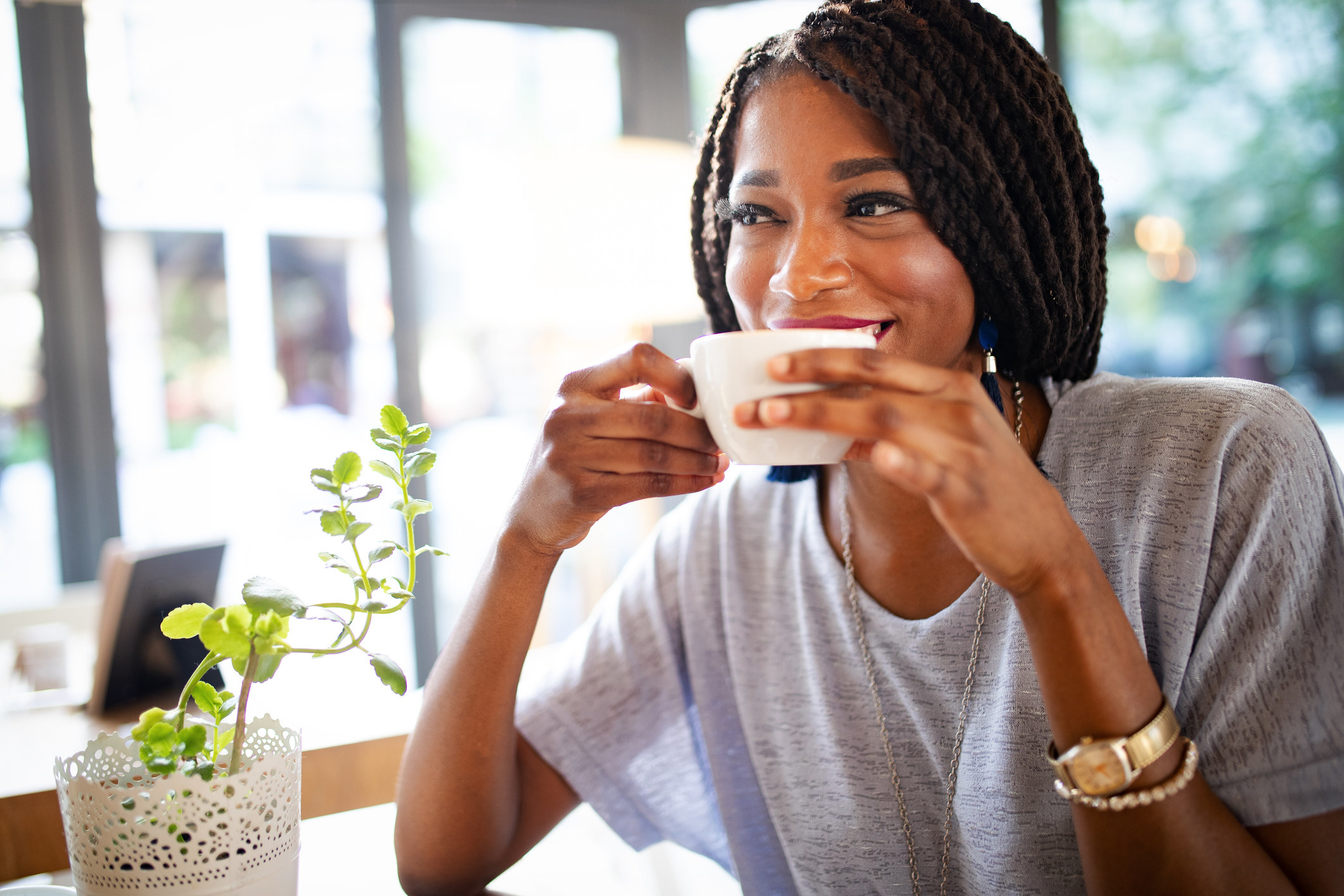 Woman smiling and sipping coffee.