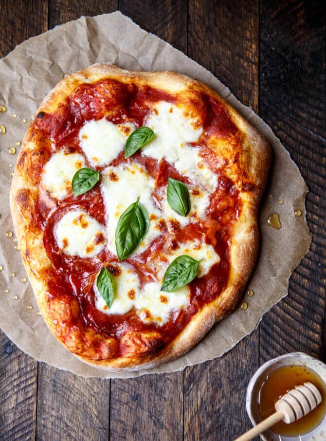 A Neopolitan-style pizza topped with tomato sauce, melted mozzarella, basil, and hot honey. 
