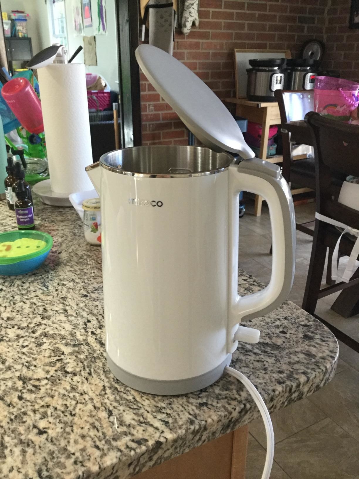 A white electric tea kettle with a gray top and grat accents at the base and handle