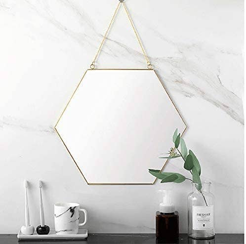 The hexagon wall mirror hanging in a bathroom. 