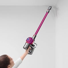 The vacuum without the floor head, but with the long piece still attached, being used to clean a corner of the ceiling