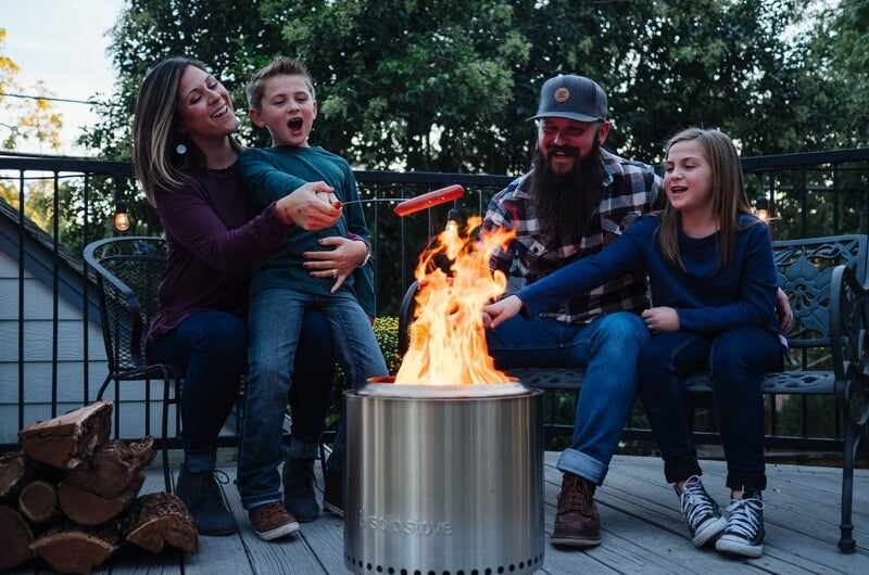 Family using the fire pit to cook hot dogs on a stick