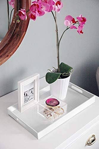 The decorative tray on a side table with decor neatly arranged on top of it. 