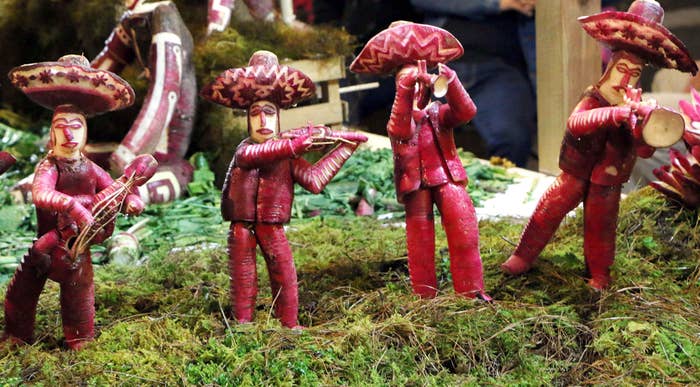 Three human figures (carved out of radishes) wearing sombreros and playing musical instruments