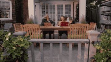 Grace and Frankie from Grace and Frankie sitting on their patio, cheering joyfully