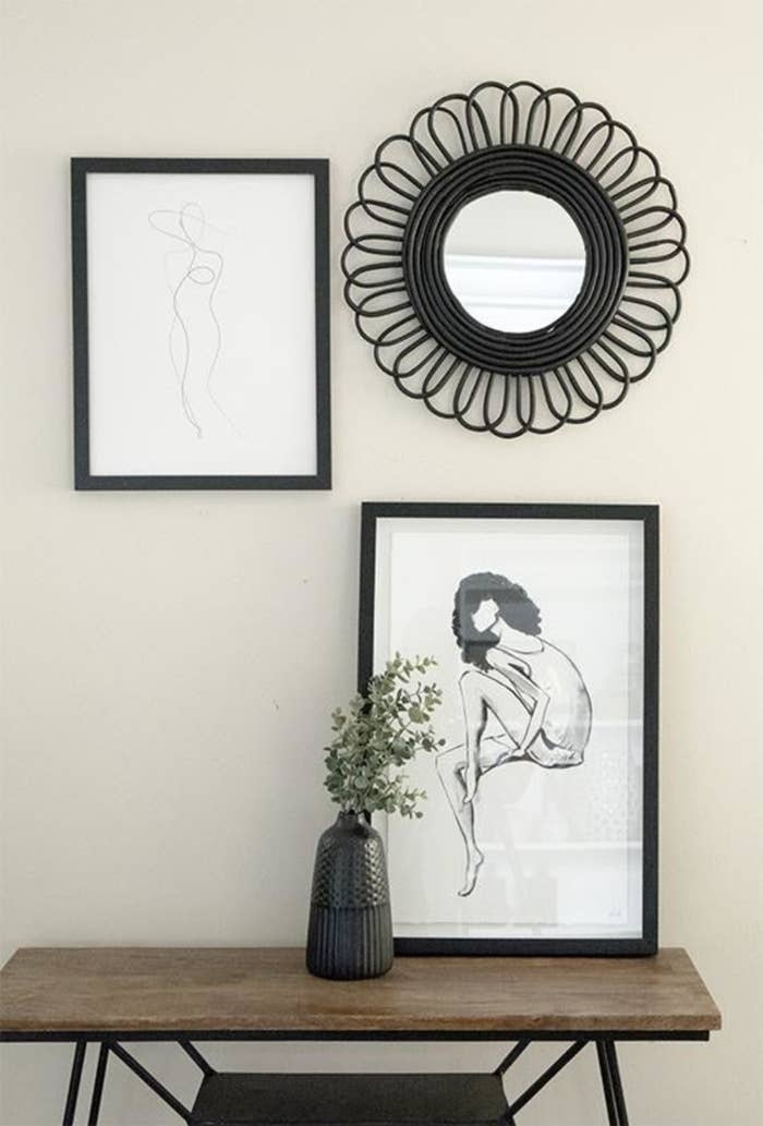 Line art print that looks like a model wearing a hat with a black frame as part of a gallery on a wall