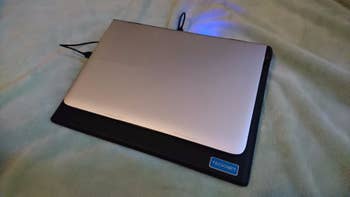 The cooling pad with a 13-inch laptop on it showing that there's still a little bit of room leftover on the pad