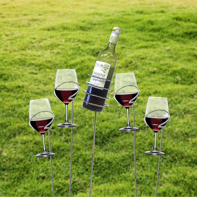The wine sticks holding glasses and a wine bottle above the ground 