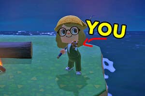 An "Animal Crossing" player stands near the ocean and shows off a clownfish she caught with a bold arrow pointing to her and the word "you" underneath it